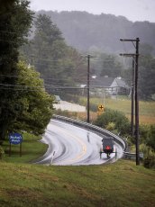 An Amish buggy travels down a long stretch of road